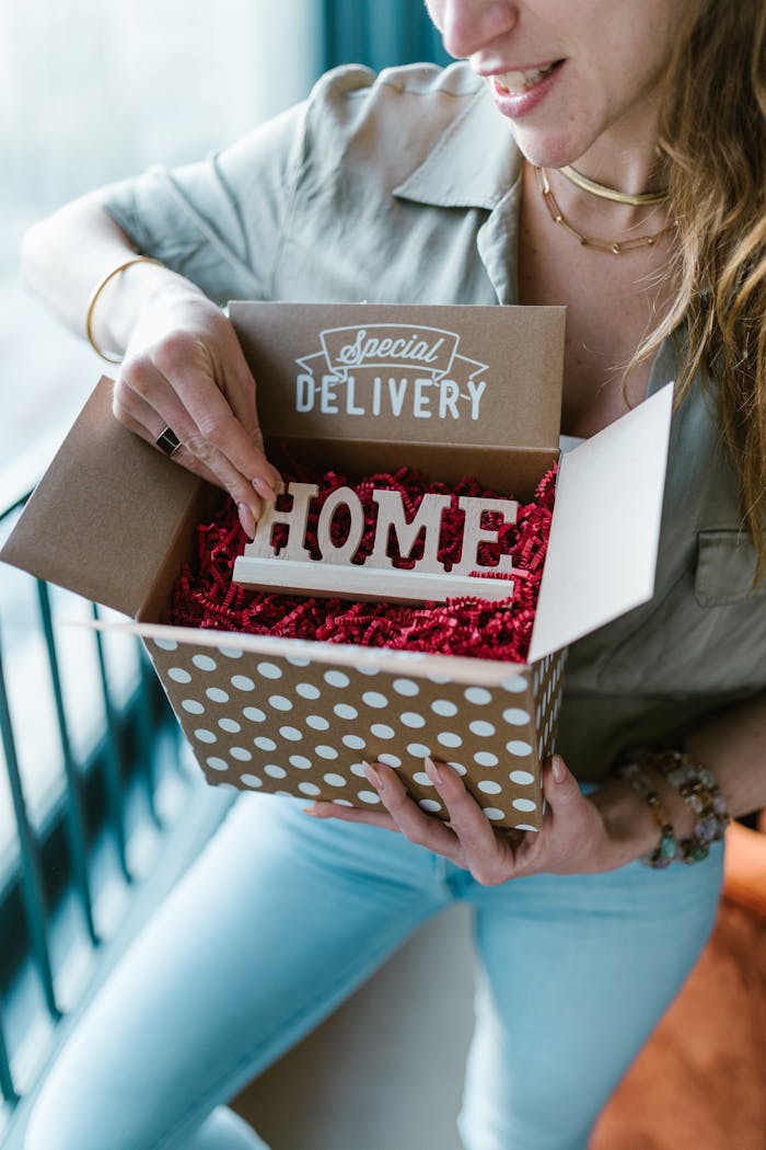 A woman opening a polka dot box labeled 'Special Delivery' with 'HOME' inside.